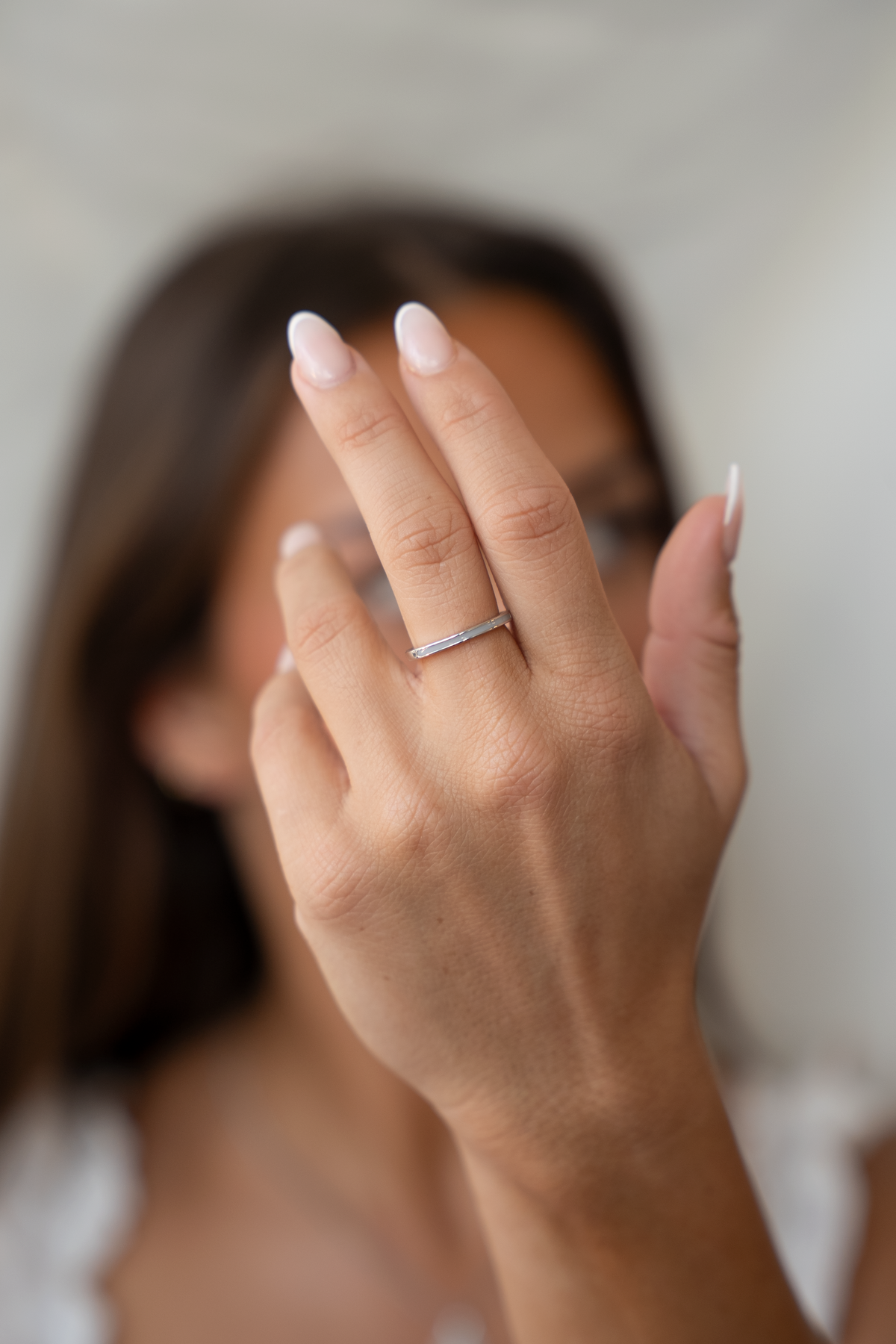 Erhobene Hand vor dem Gesicht einer Frau mit dem schmalen Eva Muttermilchring am Ringfinger