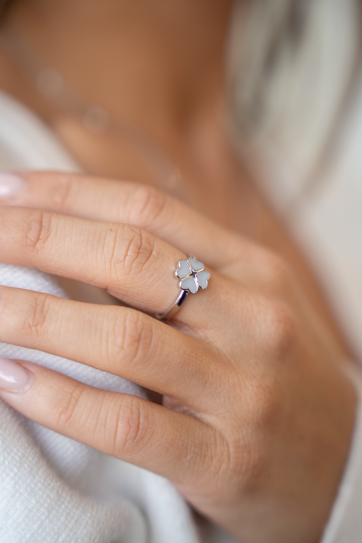 Nahaufnahme des silbernen Rings Lucy am Finger: Kleeblatt aus vier mit Muttermilch gefüllten Herzen