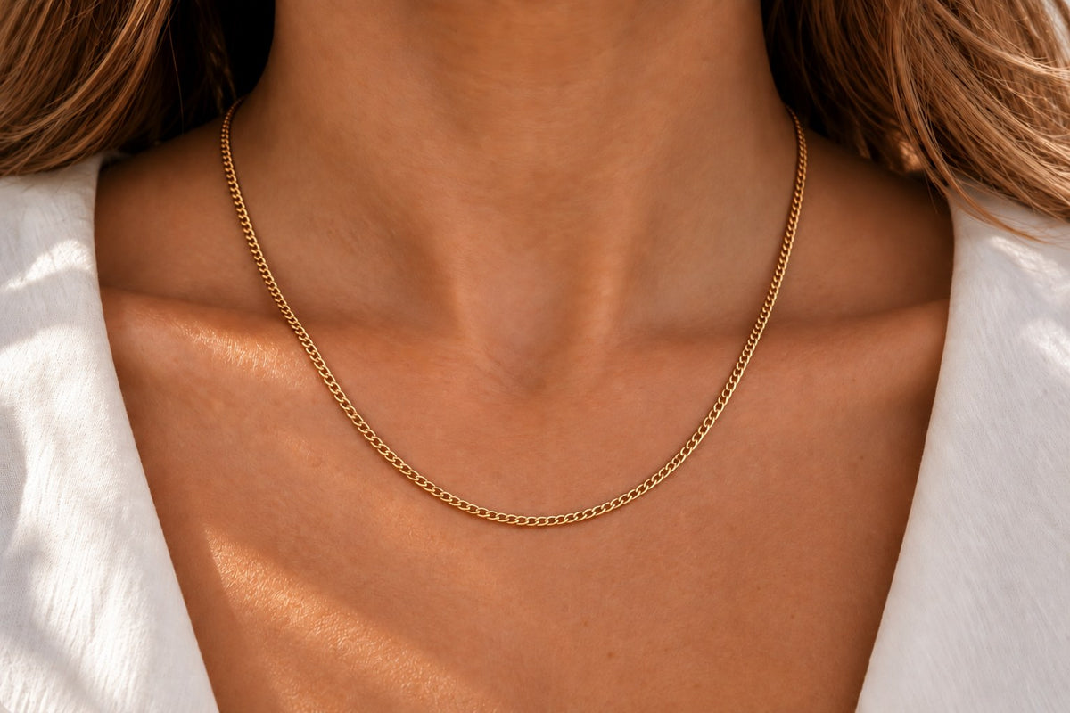 Kette aus gelbgoldfarbenem Metall mit feiner, klassischer Gliederung, die sanft am Hals liegt.