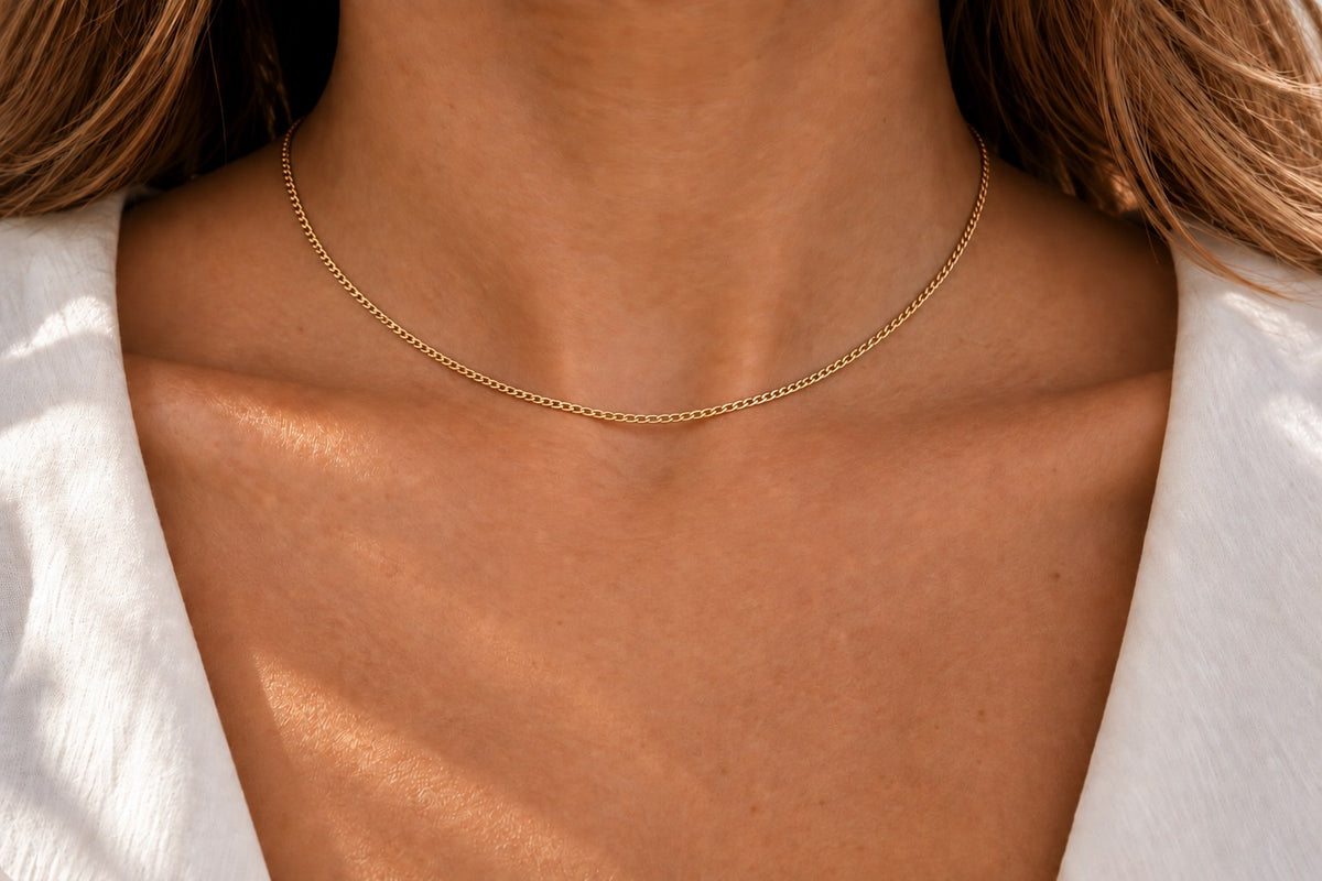 Feine Kette aus gelblich-goldenem Metall, zart und schlicht, liegt sanft am Hals.