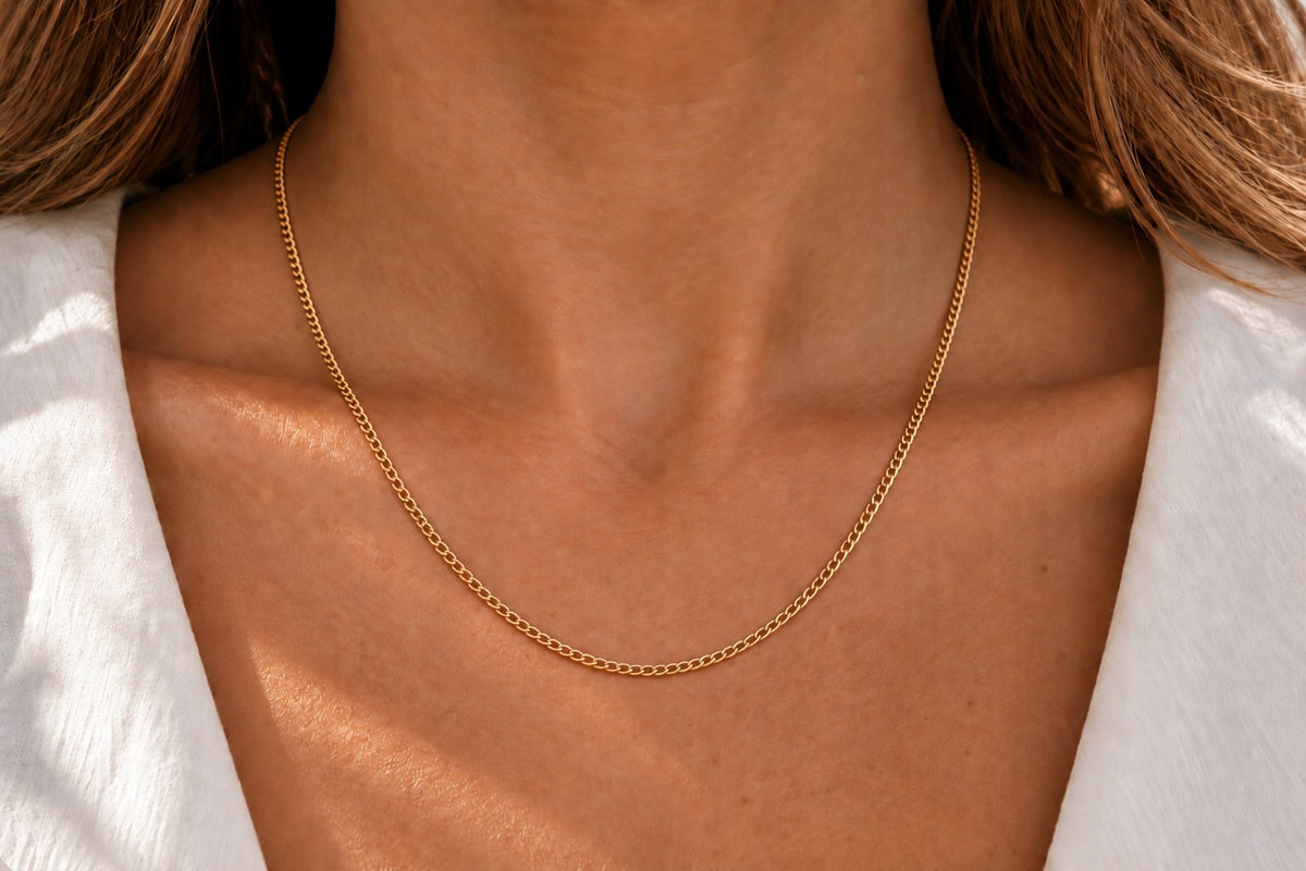 Feine Kette aus gelblich-goldenem Metall mit schlichten, glänzenden Gliedern, die sanft am Hals liegt.