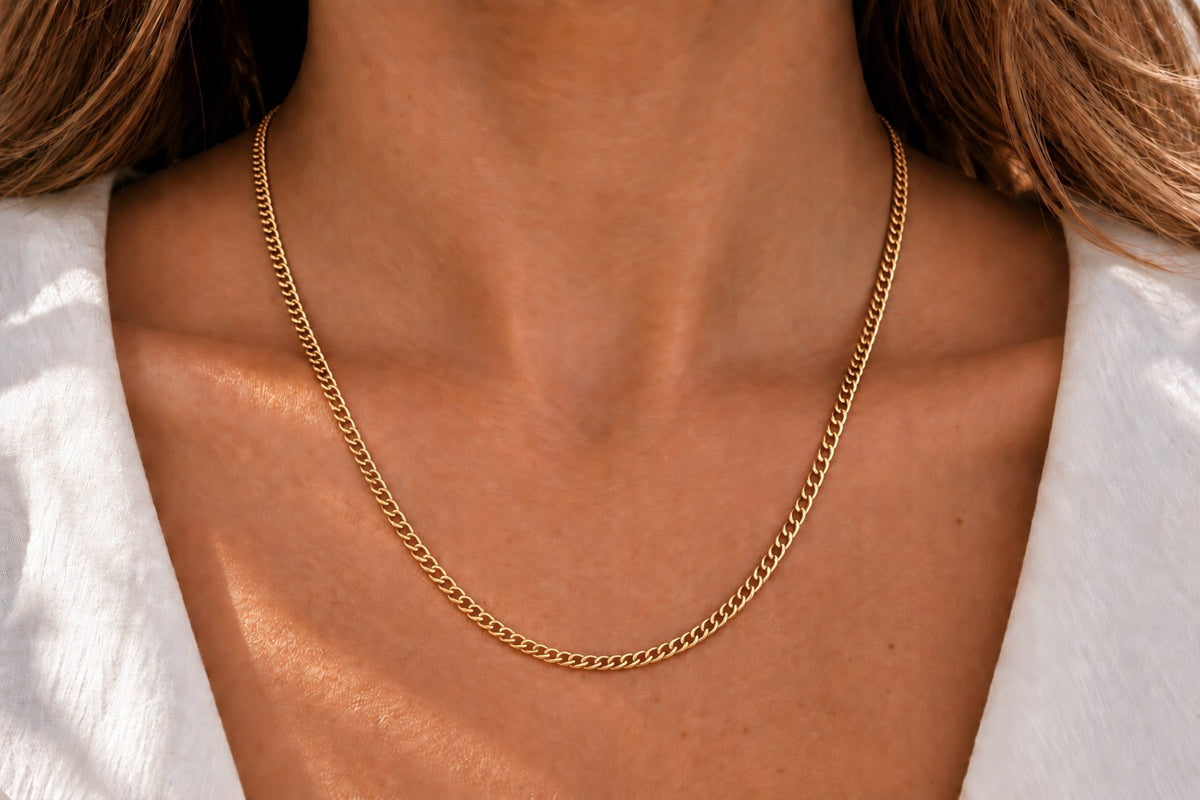 Kette aus glänzendem, gelbgoldenem Metall mit einer klassischen Gliederstruktur, die elegant am Hals liegt.