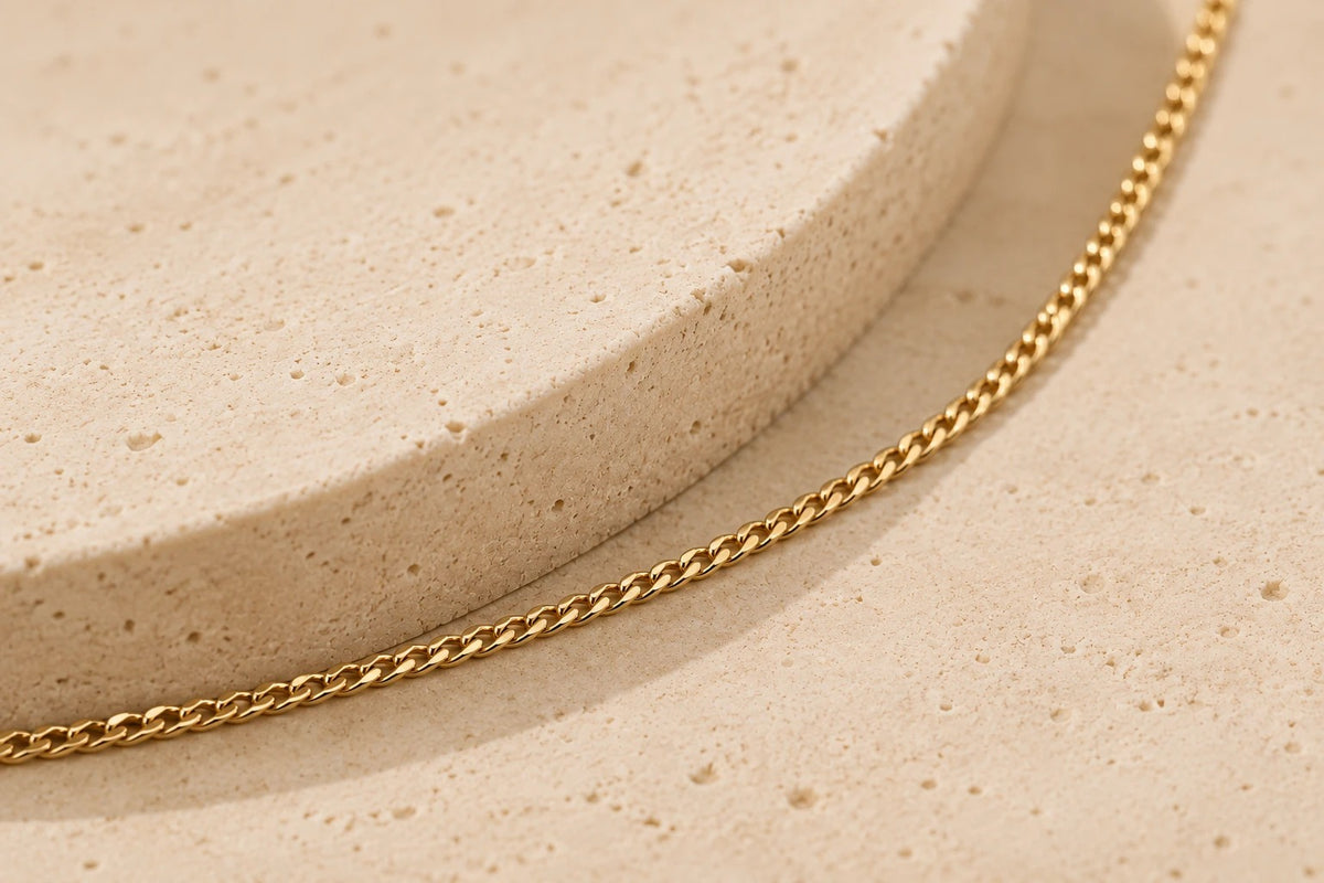 Feine Kette aus glänzendem Gelbgold mit zarten, geflochtenen Gliedern auf einem neutralen Untergrund.