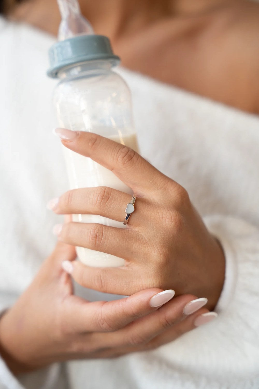Mutter hält eine Flasche Muttermilch und trägt einen Muttermilchring